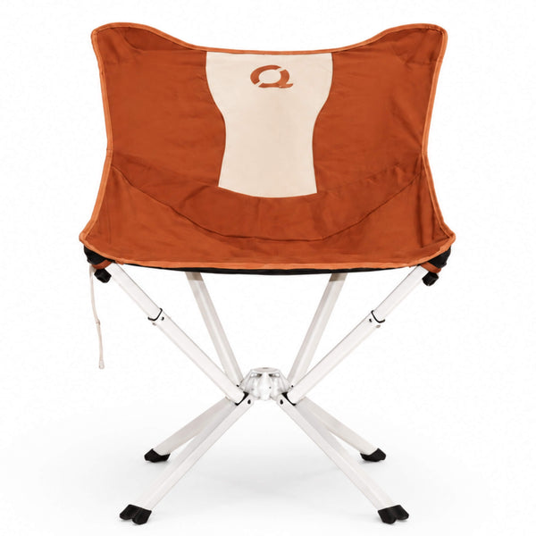 A folding camp chair in canyon orange fabric seat and backrest, featuring a cream-colored vertical panel on the backrest with a stylized orange letter CLIQ Q logo. The chair has a white metal folding frame with black plastic feet and leg caps, shown against a plain white background. Limited Edition MystiQ Canyon Orange - CLIQ
