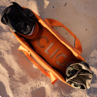Orange bag with 'CLIQ' branding on a sandy surface - ToQ