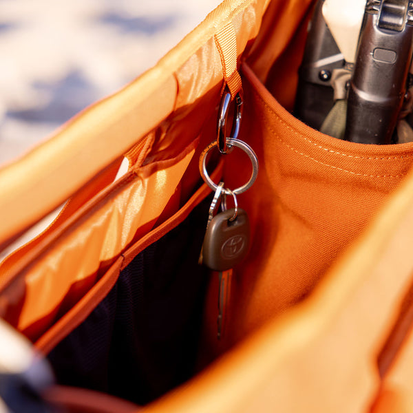 Close-up of an orange bag with keys hanging from a hook, blurred water background